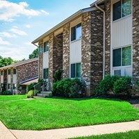 A building with a brown and beige exterior with a green lawn in front.